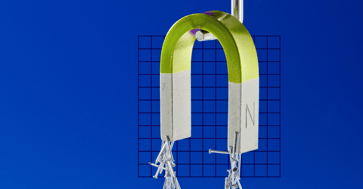 Green magnet pulling staples to it with a blue background.