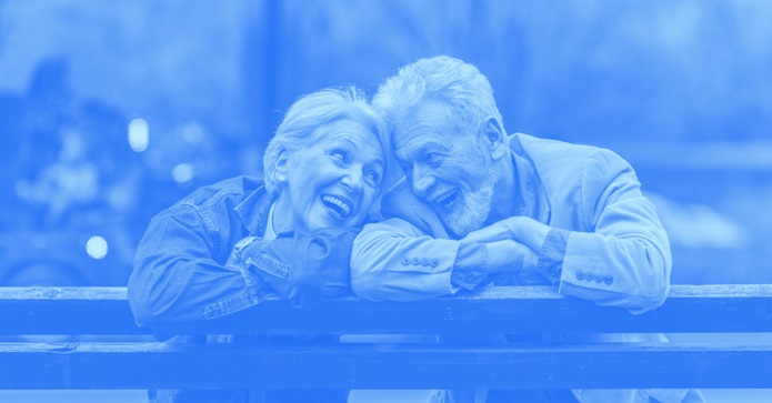 Elderly couple happily looking at each other while sitting on a bench.